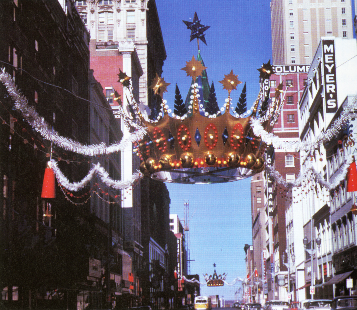 Christmas crown suspended above a busy downtown intersection – ca. 1960s