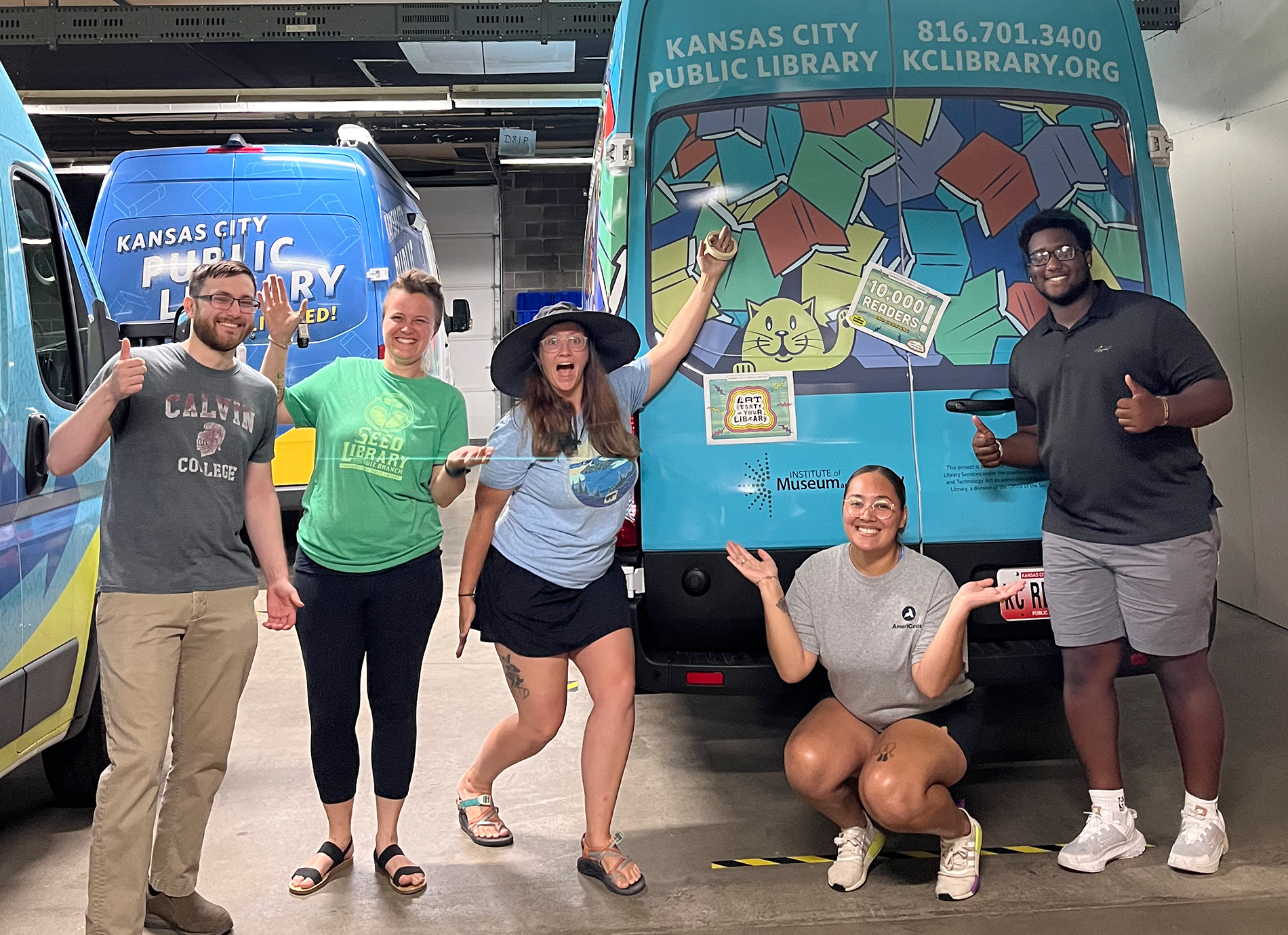 Group of library staff members with library vehicles