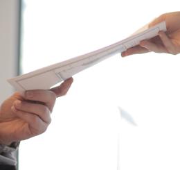 person handing paper to another