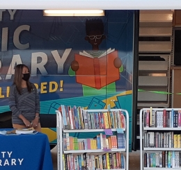 bookmobile with books on carts and staffer behind table