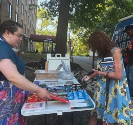 Library staffers show patrons books at a Bookmobile stop at Nowlin Apartments.