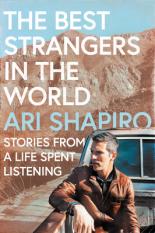 A photo of Ari Shapiro on the back of a truck on a dirt road in front of a mountain