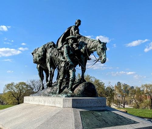 Profile image of a  statue of woman on horseback and one man visible leading the horse