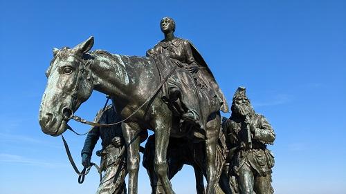statue of woman on horseback with two men flanking her