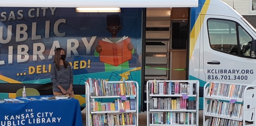 bookmobile with books on carts and staffer behind table